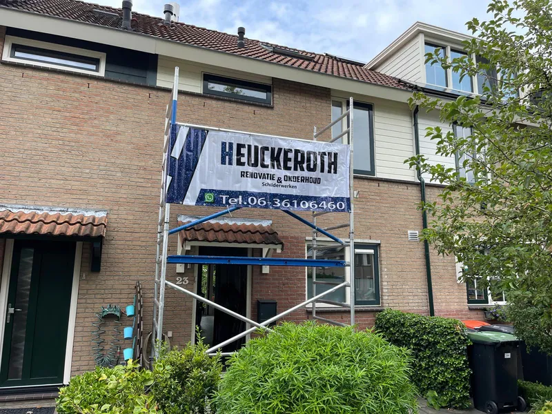 Schilder brengt verf aan op buitenkozijn van een woning